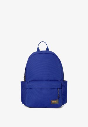 Robust blå rygsæk med frontlomme med lynlås, sidelommer, topgreb og Timberland-logo på nederste højre hjørne.