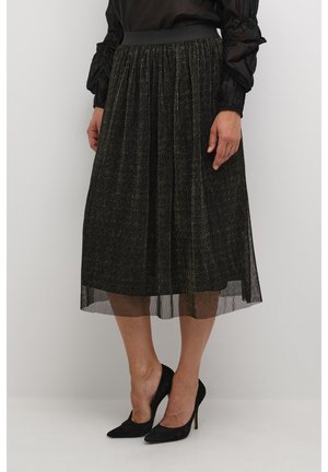 Jupe midi noire scintillante avec taille froncée et superposition transparente ; associée à des talons hauts noirs. Le tissu texturé ajoute un intérêt visuel.