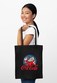 Czarna torba na ramię z tkaniny z vintage'owym logo Coca-Coli, przedstawiającym Świętego Mikołaja pijącego napój, na niebieskim okrągłym tle.