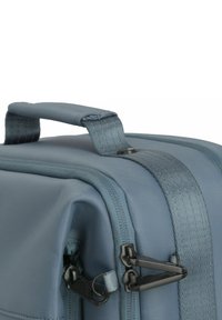 Grijze stoffen rugzak met een gestructureerd oppervlak, een stevige handgreep, ritsen en zwarte hardware-accenten. Rechthoekige vorm met versterkte randen.