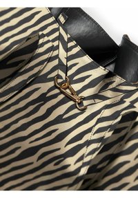 Tissu beige à rayures zèbre noires, avec un accent en cuir noir en haut et une fermeture à boucle dorée à l'avant.