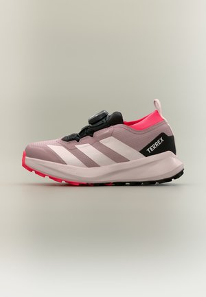 Ein einzelner rosa-schwarzer Adidas Terrex Trailrunning-Schuh mit weißen Streifen und roter Sohle, von der Seite auf schlichtem Hintergrund gezeigt.