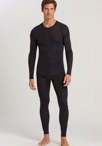 Sort langærmet termotrøje og matchende bukser, lavet af blødt stof, tætsiddende form, glat tekstur, minimale sømme og rund halsudskæring.