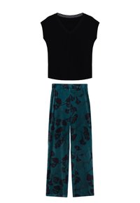 Czarny crop top w dekolcie w kształcie V zestawiony z teczowymi spodniami o szerokich nogawkach z ciemnym wzorem kwiatowym. Miękka tkanina o lekkiej teksturze i luźnym kroju.