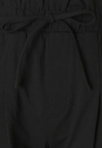 Pantalon de jogging noir avec une taille élastique munie d'un cordon de serrage, des poches latérales et un tissu doux et texturé.