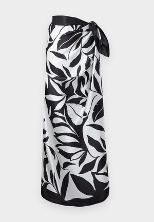 Czarno-biały sarong w liściasty wzór, zawiązany w talii, wykonany z gładkiej, jedwabistej tkaniny.