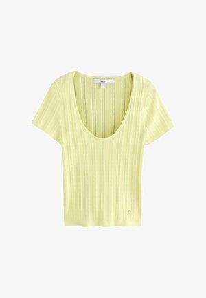 Hele kollane lühikeste varrukatega kootud top, millel on kaarjas kaelus ja vertikaalne soonikmustri, väike metallist logo alläärde lähedal.