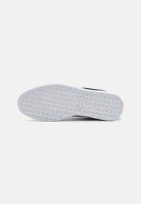 Sneaker sole featuring a textured white rubber base with a geometric pattern. Black accents along the sides.