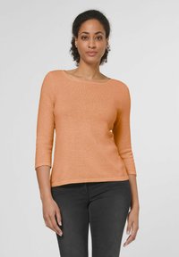 Langärmelig, ronde hals top in zachte perzik gebreide stof. Kenmerkend voor een getailleerde silhoutte en geribde manchetten, gecombineerd met donkere jeans.