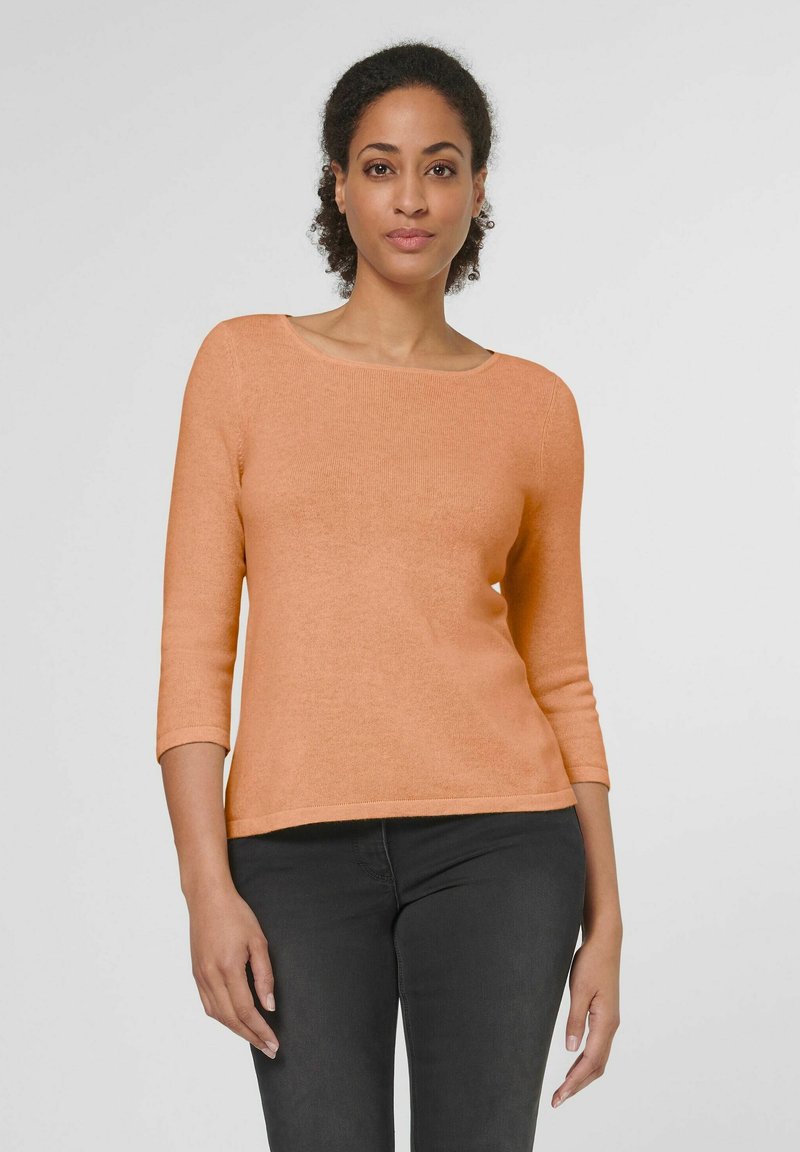 Langärmelig, ronde hals top in zachte perzik gebreide stof. Kenmerkend voor een getailleerde silhoutte en geribde manchetten, gecombineerd met donkere jeans.