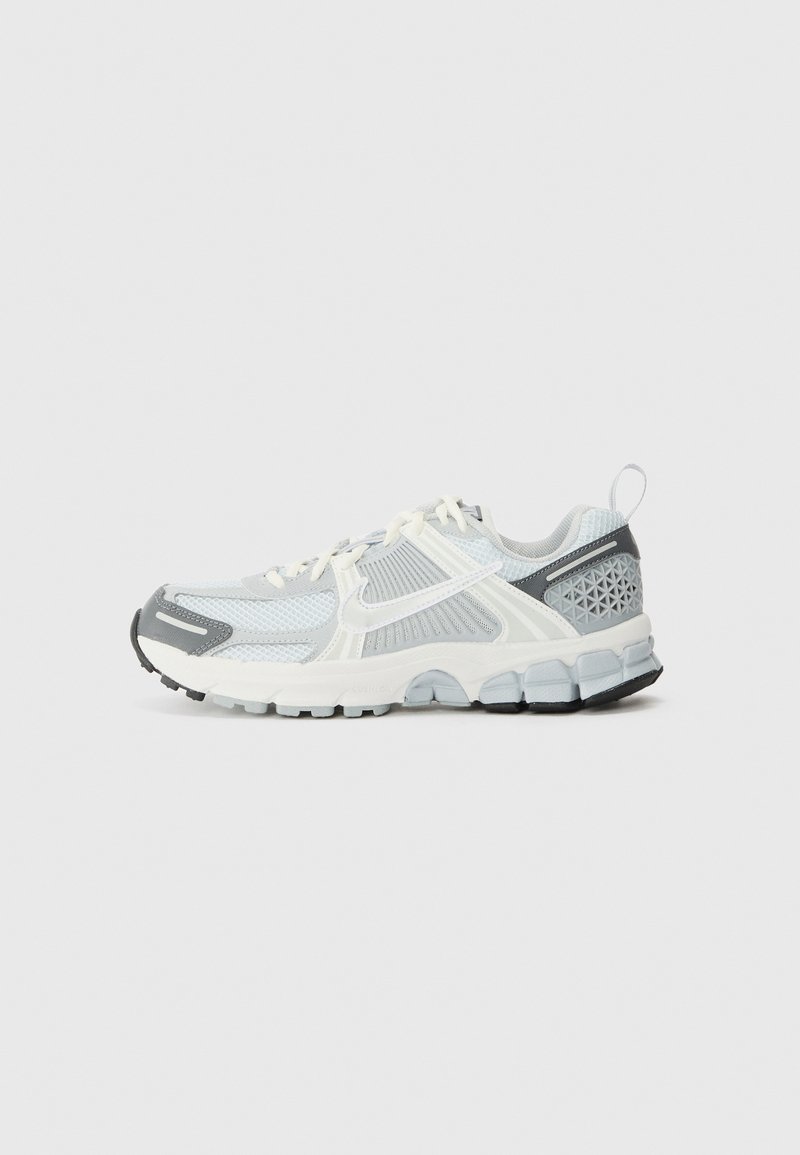 Chaussure de sport légère avec une tige en mesh blanc et gris clair, des accents texturés, une semelle rembourrée et une semelle extérieure en caoutchouc noir.
