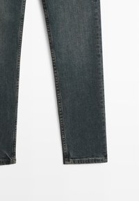 Dark wash denim jeans with a straight-leg design, featuring a minimalistic style and clean, unfinished hems.