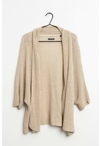 Beige, öppen cardigan med lös passform, långa ärmar och en texturerad stickad mönster. Hänger från en svart krok.