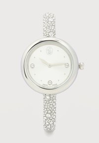 Στρογγυλό ασημένιο ρολόι χειρός με λευκό καντράν, ενδείξεις ωρών από κρύσταλλα, λουράκι με κρυστάλλους και ετικέτα "Κατασκευασμένο στην Ελβετία" στο καντράν.