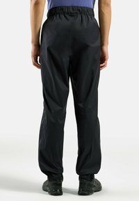 Zwarte waterdichte broek met een elastische tailleband. Heeft een comfortabele pasvorm, een gladde textuur en boorden die zijn ontworpen voor gemakkelijke beweging.