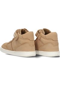 Beige hoge sneakers met klittenband, leren bovenkant, witte rubberen zool en subtiele stikdetails aan de zijkanten.