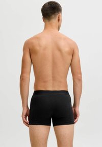 Black cotton boxer briefs with a wide elastic waistband. Smooth texture, fitted design, and mid-thigh length. No visible patterns or logos.