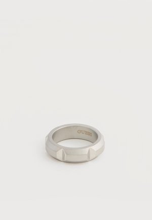 Strieborný kovový prsteň s vystúpenými obdĺžnikovými akcentmi po obvode a vyrytou značkou "GUESS" na vnútornej strane.