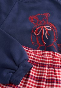Lauluhtava merilaevade kleit, millel on punane tikitud karu ja punane ruuduline seelik. Sisaldab ribakäeosi ja elastset vööd.