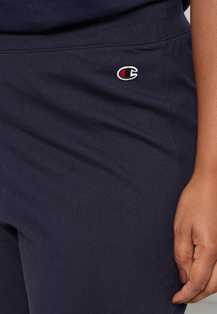 Pantalon de sport bleu marine en mélange de coton doux avec une taille élastique ; présente un petit logo brodé sur la hanche.