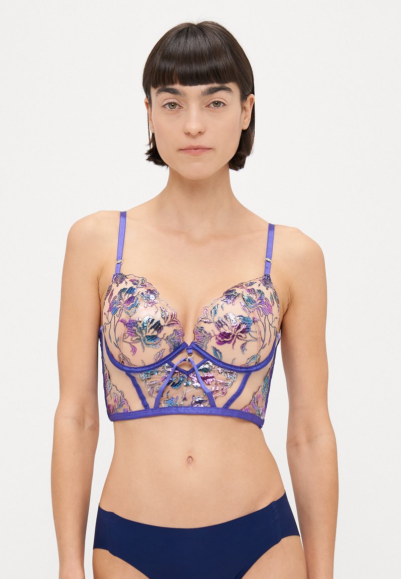Spids-bralette med en gennemsigtig mesh-krop, livlig blomsterbroderi i lilla og blå, med en struktureret undertråd og justerbare stropper.