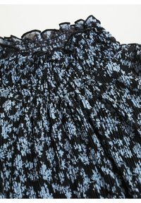 Robe à motifs bleus et noirs avec un col à volants et une texture plissée, présentant un corsage smocké et un motif floral.