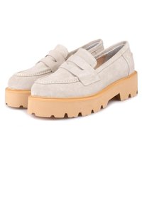 Mocassins en daim beige avec une semelle en caoutchouc épaisse et surélevée. Présentent un design à bride sur le dessus et des détails cousus le long des bords.