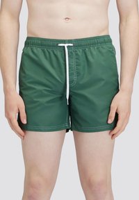 Groene zwembroek gemaakt van synthetisch materiaal, met een elastische tailleband voorzien van een witte koord en contrasterende witte stiksel.