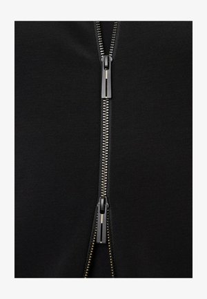 Felpa nera con zip metallica color argento e cursore testurizzato, con cuciture flatlock lungo i bordi.