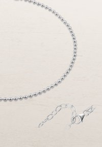 Silver bead necklace featuring a uniform round shape, smooth texture, and a secure lobster clasp with a chain extension for adjustable length.