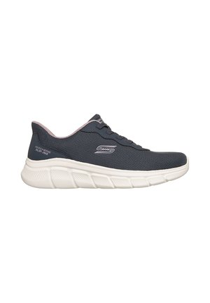 Deportivas sin cordones Skechers en color gris oscuro con suela blanca gruesa y forro interior rosa, con logo lateral y cordones sobre fondo blanco.