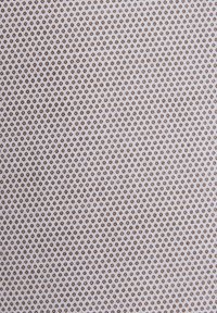 Tissu blanc avec un motif répétitif de petits points hexagonaux uniformément espacés en tons marron et beige.