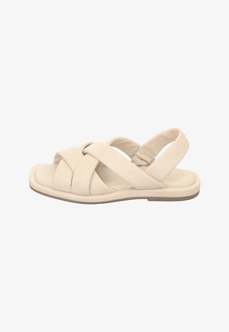 Beige sandal with crossed straps, made of soft material. Features a flat sole with a slight grip and padded back strap for comfort.