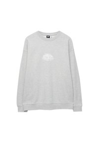 Sweat-shirt gris en coton doux, avec un col rond et des manches longues. Il présente un petit design de texte graphique blanc à l'avant.