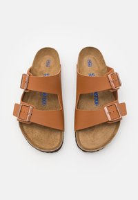 Brown leather sandals with two adjustable straps and silver buckles, featuring a textured cork footbed and a flexible rubber sole.