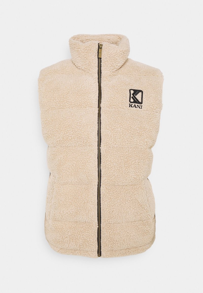 Vaatevaaleanbeige fleece-liivi, jossa on korkea kaulus, etuvetoketju ja KANI-logo. Tekstuuri kangas, pehmustettu malli, hihaton tyyli ja vastakkaisen värinen vetoketju.
