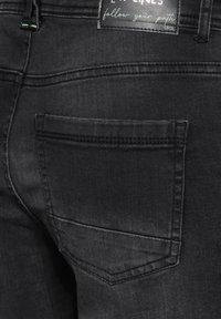 Black denim jeans with five-pocket design, featuring a single back pocket and subtle stitching details. Fabric has a smooth texture.