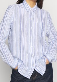 Camicia a maniche lunghe a righe azzurro chiaro e bianco con colletto button-down, taschino anteriore e vestibilità comoda. Realizzata in un tessuto testurizzato.