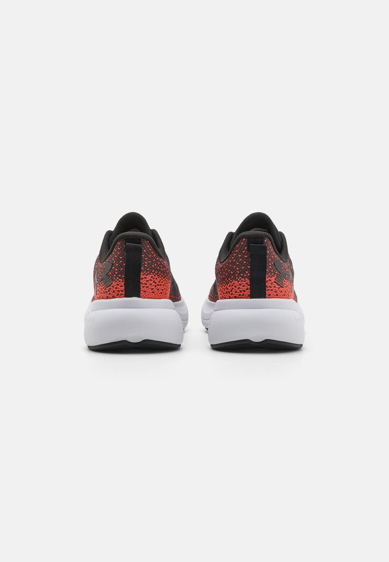 Des chaussures de sport rouges et noires avec une tige en tricot texturé, une semelle intermédiaire blanche rembourrée et des accents noirs au niveau du talon et du logo.