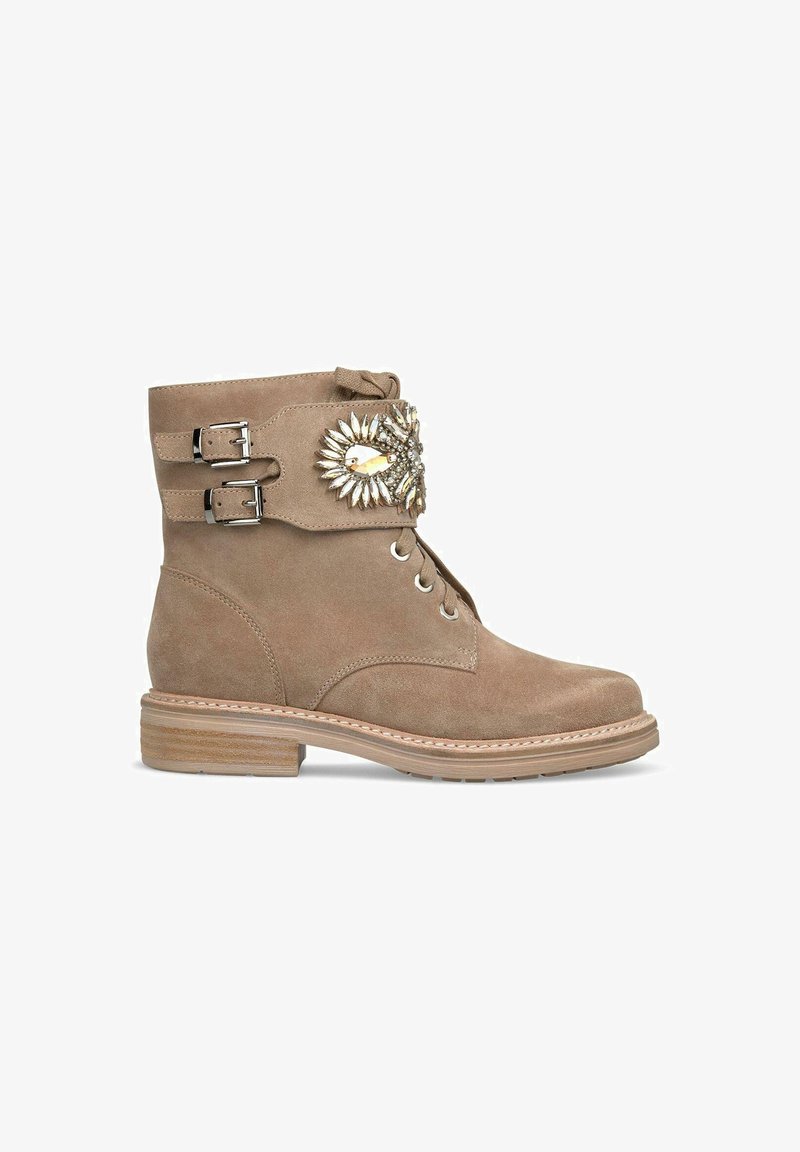 Beige suède enkellaars met dubbele gespdetail, decoratieve edelsteenaccenten, ronde neus en een gestapelde houten hak.