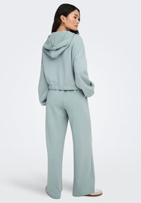 Ensemble bleu clair composé d'un sweat à capuche doux et d'un pantalon large assorti. Comprend une capuche, une coupe décontractée et une taille élastique pour le confort.