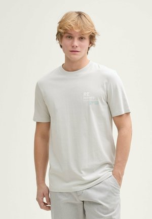 Camiseta gris claro de tejido suave, con cuello redondo, mangas cortas y texto impreso en blanco y azul en el pecho.