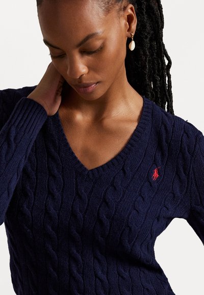 Jūrinės mėlynos spalvos švarkelis su raštuota viršutine dalimi ir V formos iškirpte, su tekstūruotais raštais ir mažuoju raudonu logotipu kairėje krūtinės pusėje. Minkšta, megzta medžiaga.