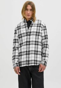 Zwart-wit geruite overhemd met klassieke kraag, lange mouwen en een borstzak, gecombineerd met donkere denim broek.