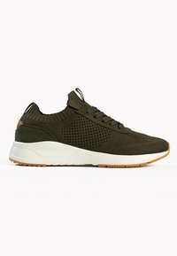 Dunkelgrüner Mesh-Sneaker mit einer strukturierten Oberseite, weißer Zwischensohle und Gummilaufsohle. Verfügt über flache Schnürsenkel und eine Zugschlaufe an der Ferse.