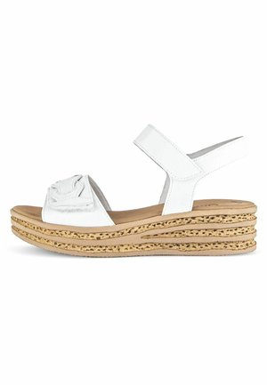 White wedge sandals with a textured cork midsole, featuring a wide strap across the foot and a soft footbed for comfort.