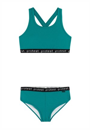 Turquoise sportieve tweedelige set met sportbeha met kruis-rug en bijpassende slip, beide met zwarte elastische banden met herhaalde "protest" tekst.