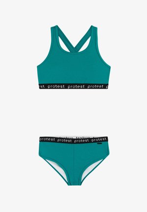 Turquoise sportieve tweedelige set met sportbeha met kruis-rug en bijpassende slip, beide met zwarte elastische banden met herhaalde "protest" tekst.