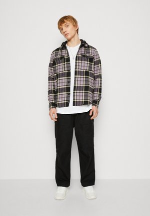 Lila- und schwarze karierte Flanellhemden mit Kapuze, Knopfleiste vorne und zwei Brusttaschen. Kombiniert mit schwarzen Cargo-Hosen und weißen Sneakern.