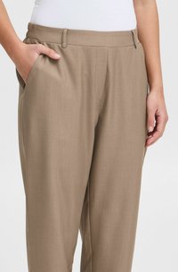 Pantalons beige ajustés avec une texture lisse, une taille élastique, des poches latérales et une coupe slim. Idéaux pour un usage décontracté ou formel.